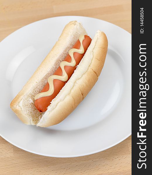 A hotdog with mustard sauce on a kitchen bench. A hotdog with mustard sauce on a kitchen bench