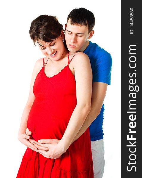 Young happy pregnant woman and her husband embracing and looking at the belly