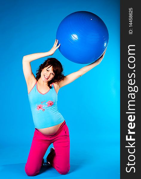 Happy beautiful pregnant woman making some exercises on a fitness ball