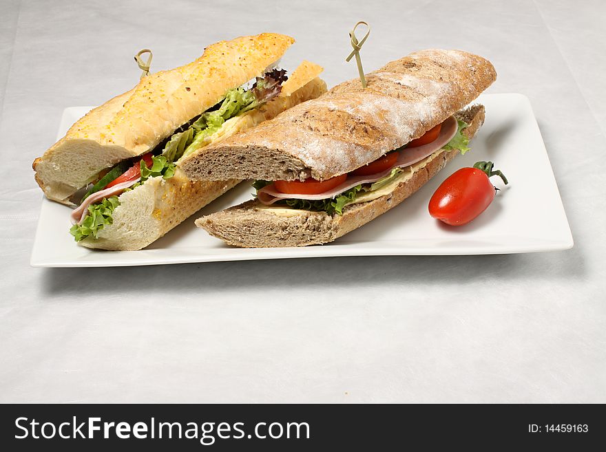 Light and dark baguettes on the white plate. Light and dark baguettes on the white plate