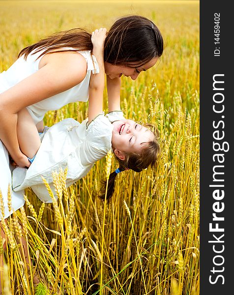 Beautiful young mother and her daughter at the wheat field on a sunny day. Beautiful young mother and her daughter at the wheat field on a sunny day