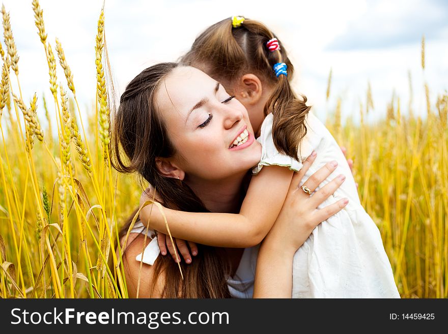 Beautiful young mother and her daughter at the wheat field on a sunny day. Beautiful young mother and her daughter at the wheat field on a sunny day