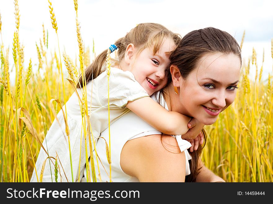 Beautiful young mother and her daughter at the wheat field on a sunny day. Beautiful young mother and her daughter at the wheat field on a sunny day