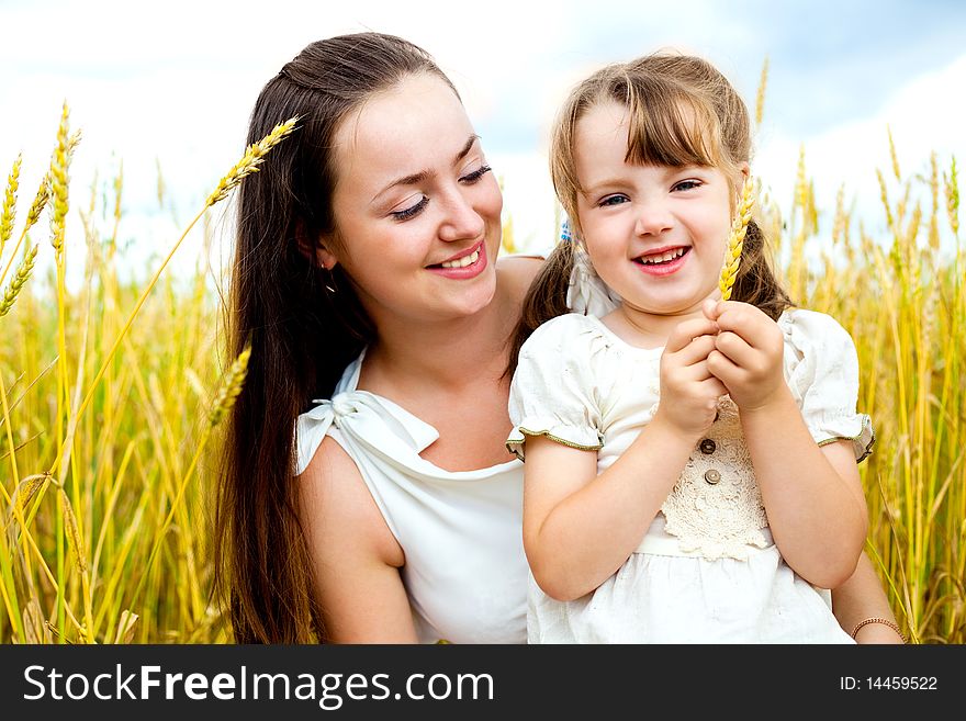 Beautiful young mother and her daughter at the wheat field on a sunny day. Beautiful young mother and her daughter at the wheat field on a sunny day