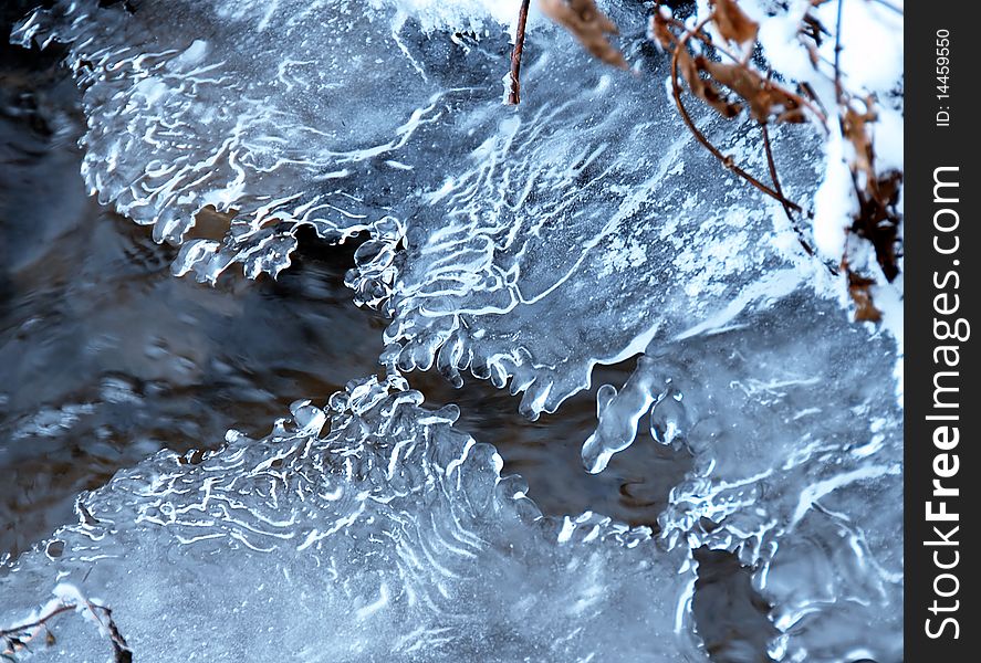 Ice crystals over flowing winter stream closeup