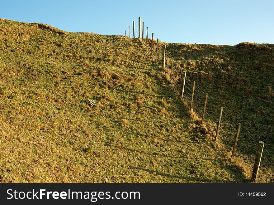 Farm fence, disappearing over hill. Farm fence, disappearing over hill.