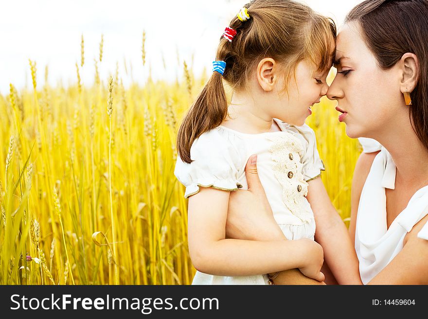 Beautiful young mother and her daughter at the wheat field on a sunny day. Beautiful young mother and her daughter at the wheat field on a sunny day