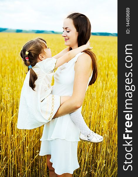 Beautiful young mother and her daughter at the wheat field on a sunny day. Beautiful young mother and her daughter at the wheat field on a sunny day