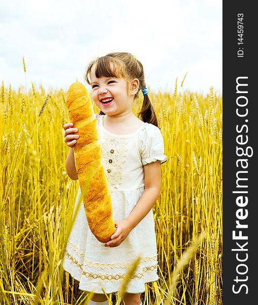 Happy cute little girl in the wheat field with a long loaf. Happy cute little girl in the wheat field with a long loaf