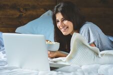 Young Woman Using Laptop And Eating Popcorn Stock Image