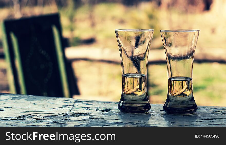 Two glasses with wine or juice on a wooden table in the garden