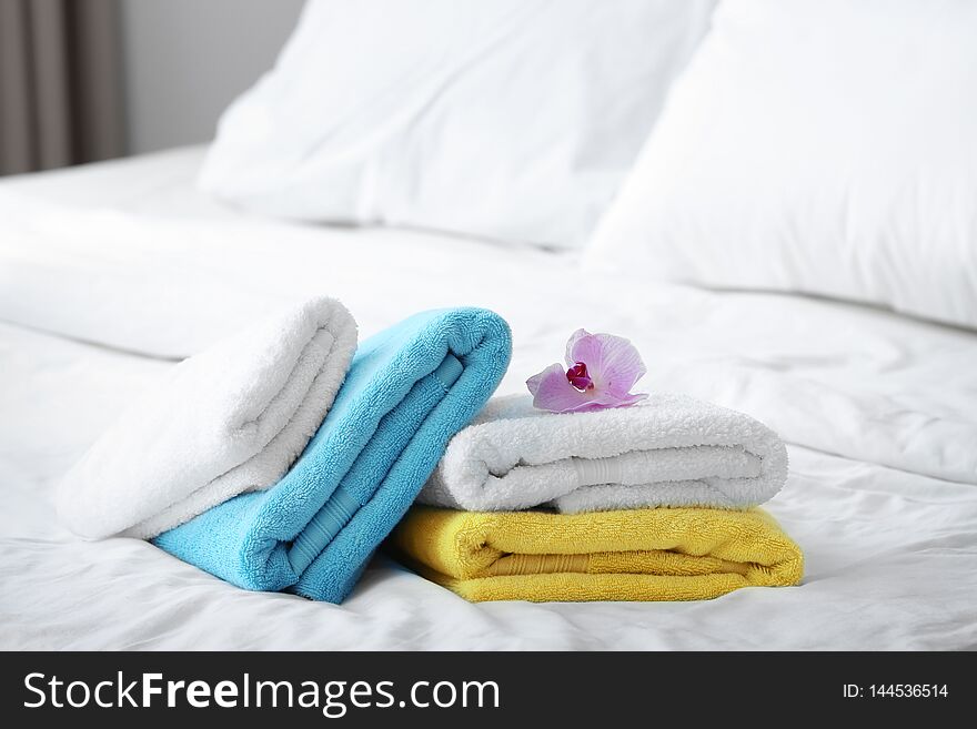 Clean towels and pink orchid on bed