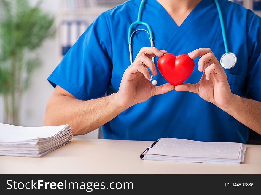 The male doctor cardiologist holding heart model