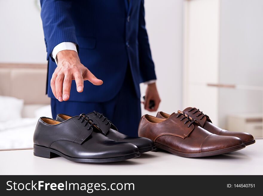 The young handsome businessman choosing shoes at home