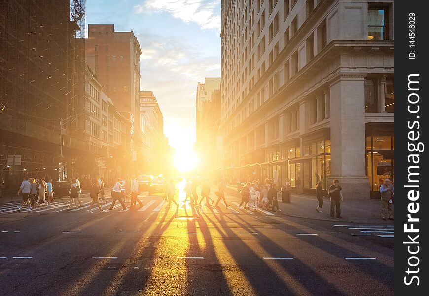 View of a busy intersection in Manhattan with sunlight shining on the people of New York City