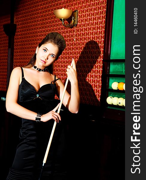 Beautiful young blond woman playing billiard in the bar