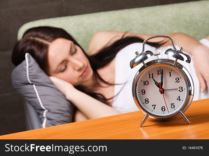 Vintage alarm clock, with beautiful young woman sleeping in the background. Vintage alarm clock, with beautiful young woman sleeping in the background