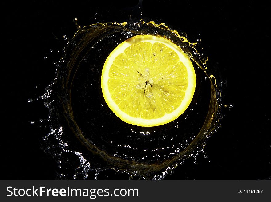 Lemon in water drops on black