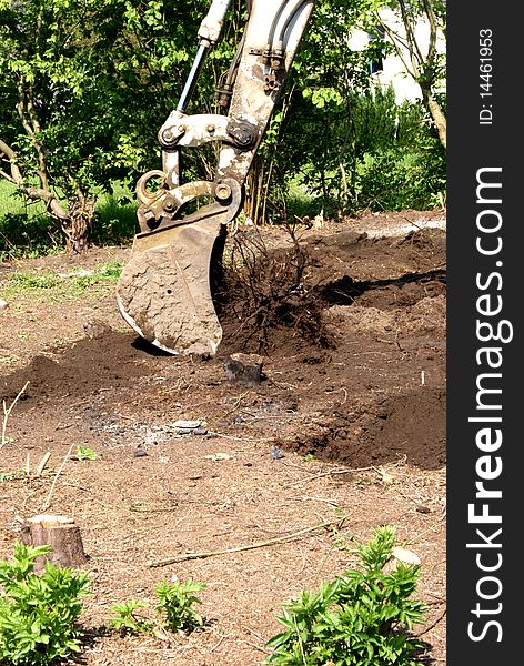 An excavator working in a garden. An excavator working in a garden