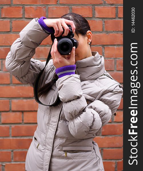 Woman photographer on the background of a brick wall