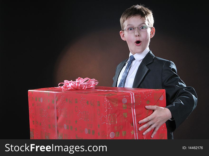 Boy in a dark suit gets on the hip bright boxes with gifts. Boy in a dark suit gets on the hip bright boxes with gifts