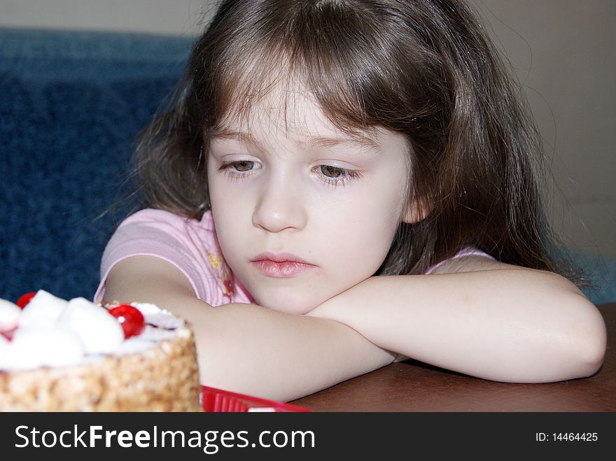 The girl with grief looking at a cake. The girl with grief looking at a cake