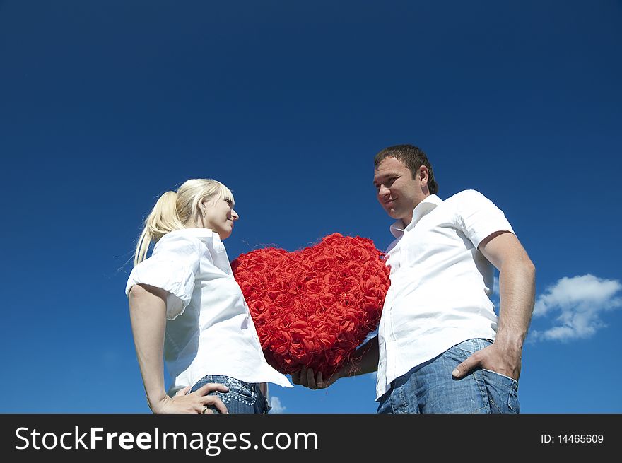 Couple of young people, loving boy and girl holding hands in the heart of roses
