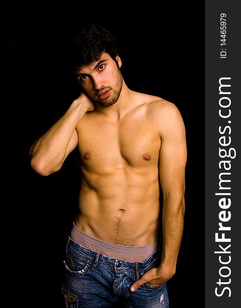 Young man with atletic body on black background