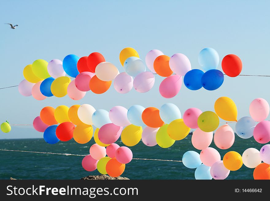 Lots of colorful balloons on background with blue sky and sea