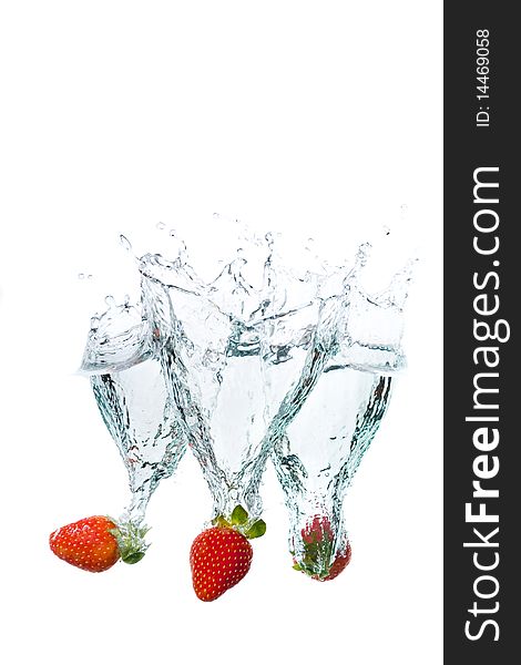 Three fresh strawberries splashing into water. Three fresh strawberries splashing into water