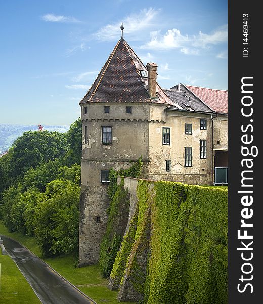 An old historical castle tower with a surrounding protection wall covered with ivy