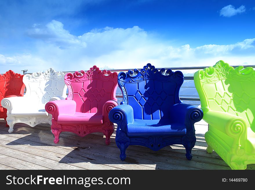 Multi-colored armchairs stand outdoor against the background the blue sky