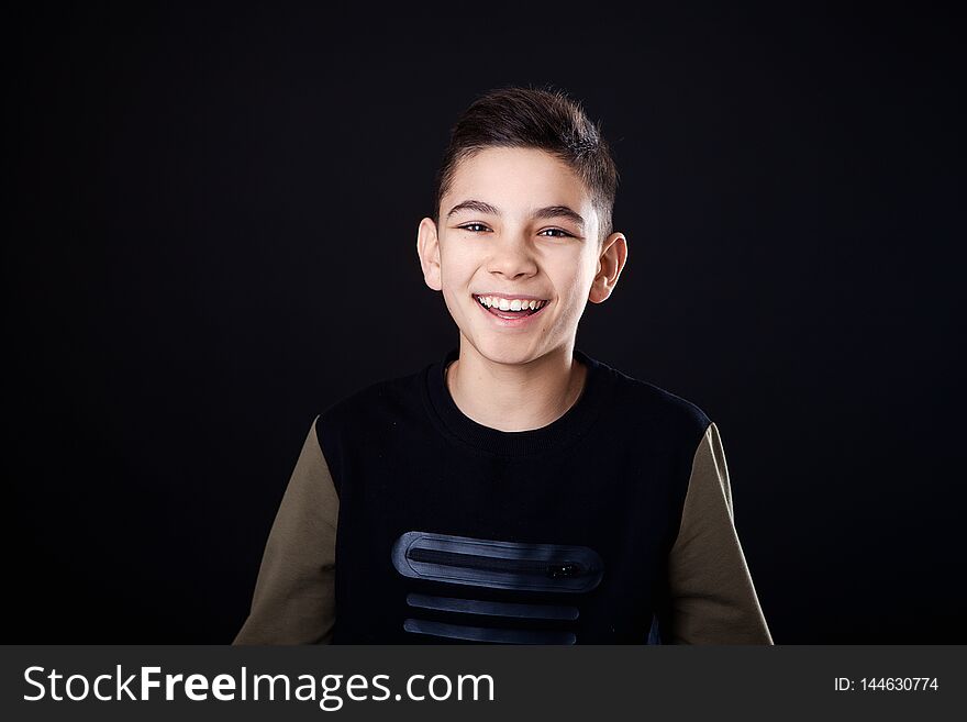 Portrait of a handsome young man smiling, on black background.