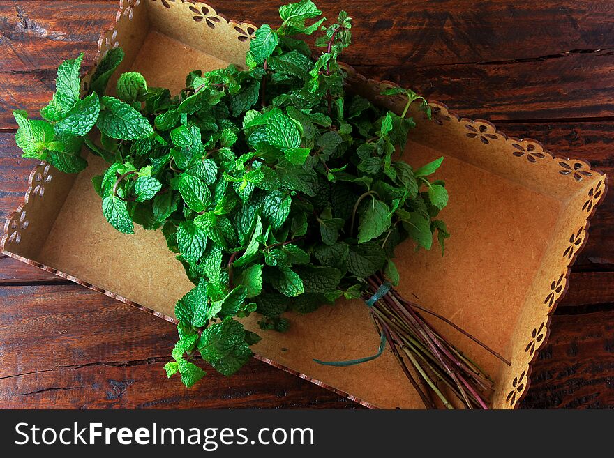 Group of green organic fresh mint in basket over rustic wooden desk. Aromatic peppermint with medicinal and culinary uses