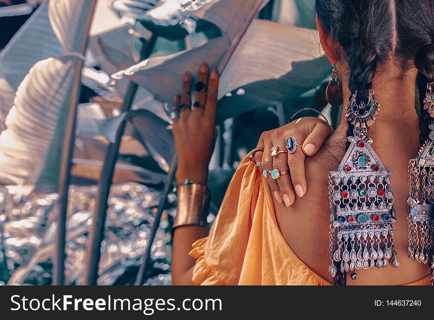 Close up of beautiful young fashionable woman with stylish boho accessories posing on natural tropical background