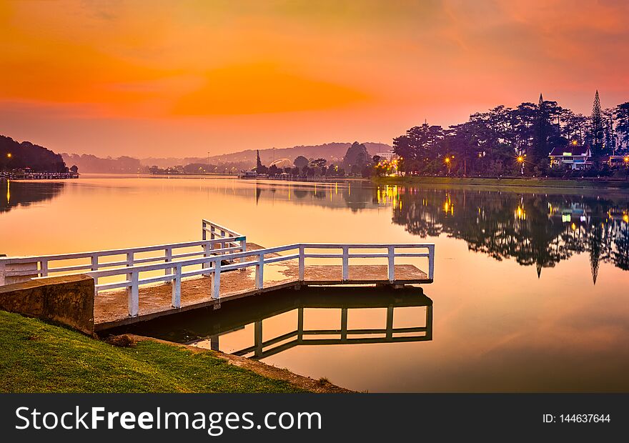 Amazing view of sunrise over Xuan Huong Lake, Dalat, Vietnam. Pier on the foreground. Landscape photo. Panorama. Amazing view of sunrise over Xuan Huong Lake, Dalat, Vietnam. Pier on the foreground. Landscape photo. Panorama