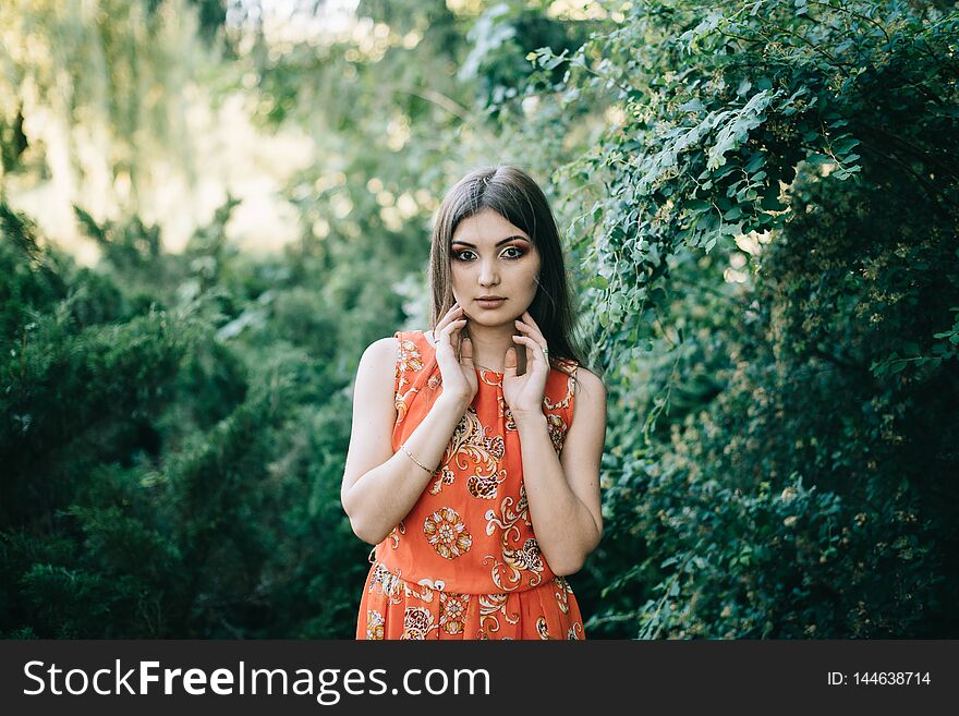 Beautiful young girl in a summer red dress in a park