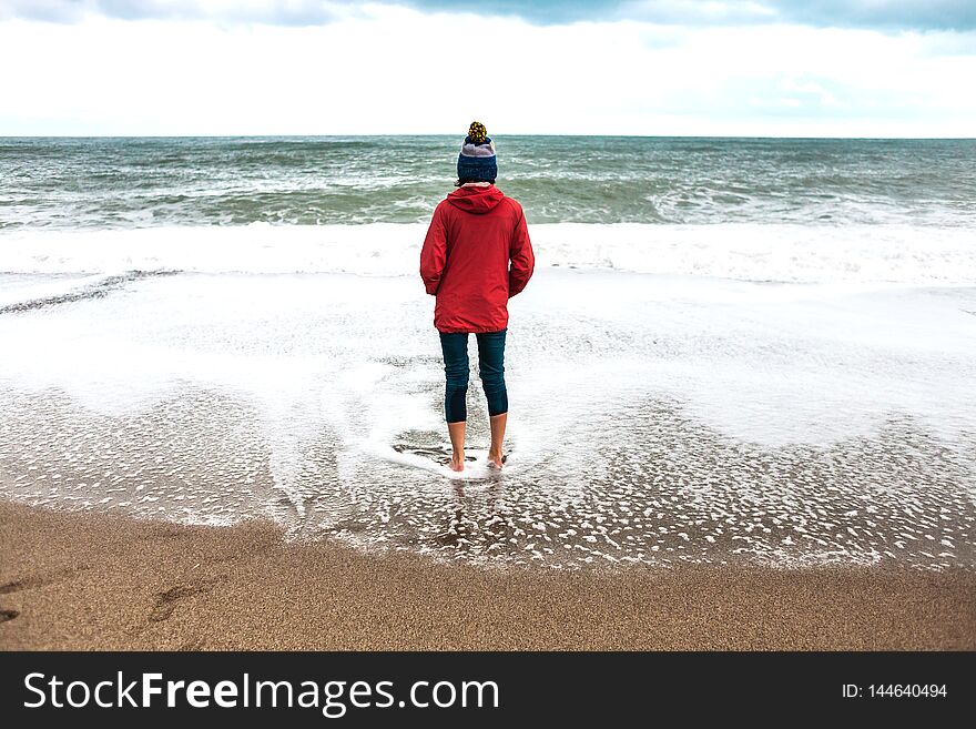 Barefoot woman looks at the winter sea