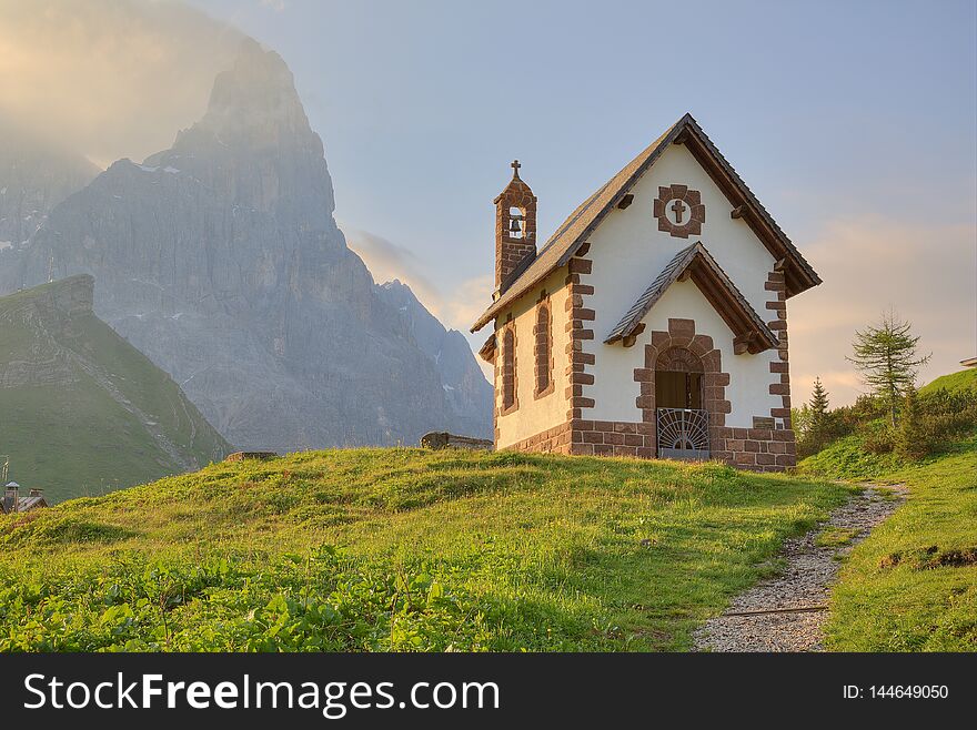 Morning scenery of a lovely church at the foothills of rugged mountain peaks  Cimon della Pala  under dramatic dawning sky in Passo Rolle, Dolomiti, Trentino Alto Adige, South Tyrol, Italy, Europe