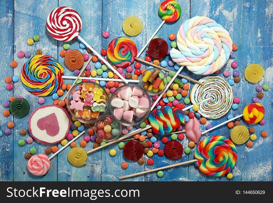 Candies with jelly and sugar. colorful array of different childs sweets and treats on blue background