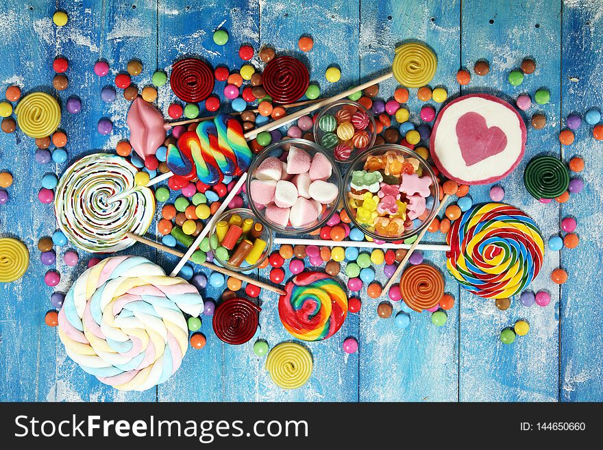 Candies with jelly and sugar. colorful array of different childs sweets and treats on blue background