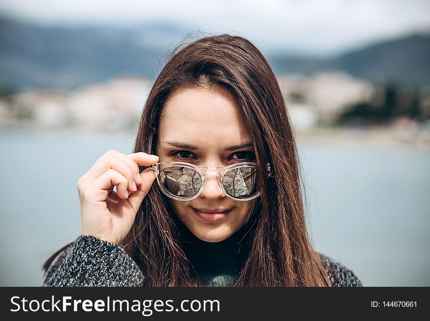 Portrait of a beautiful young fashionable girl on the background of the sea and the coastal city. Portrait of a beautiful young fashionable girl on the background of the sea and the coastal city.