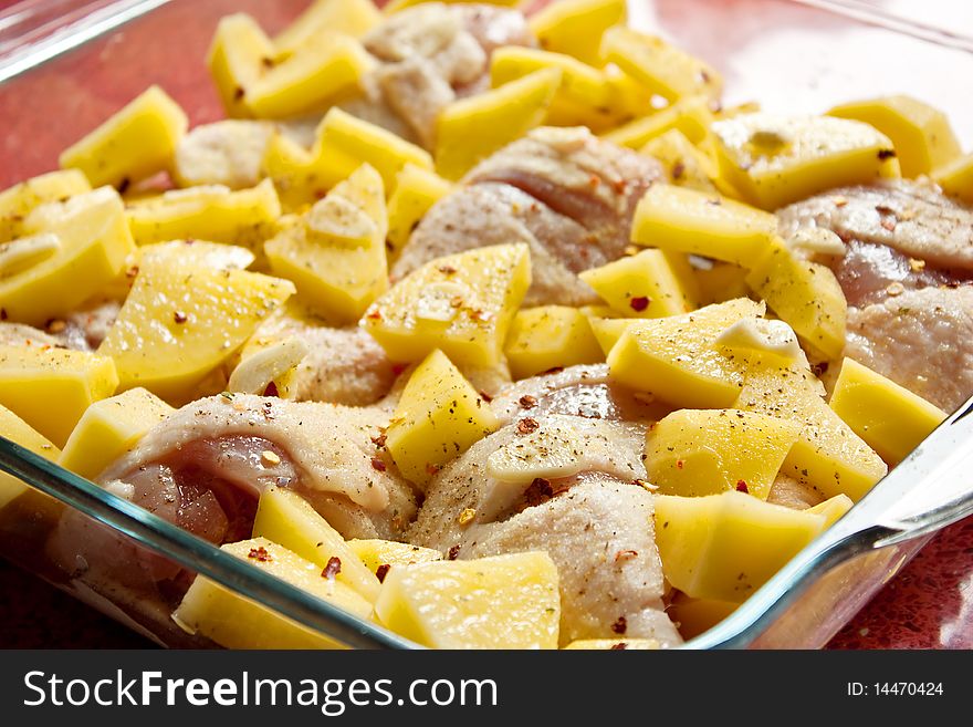 Chicken and chopped raw potatoes in a tray before the oven. Chicken and chopped raw potatoes in a tray before the oven