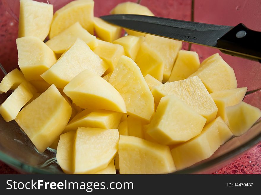 Chopped raw potatoes with knife in a bowl. Chopped raw potatoes with knife in a bowl