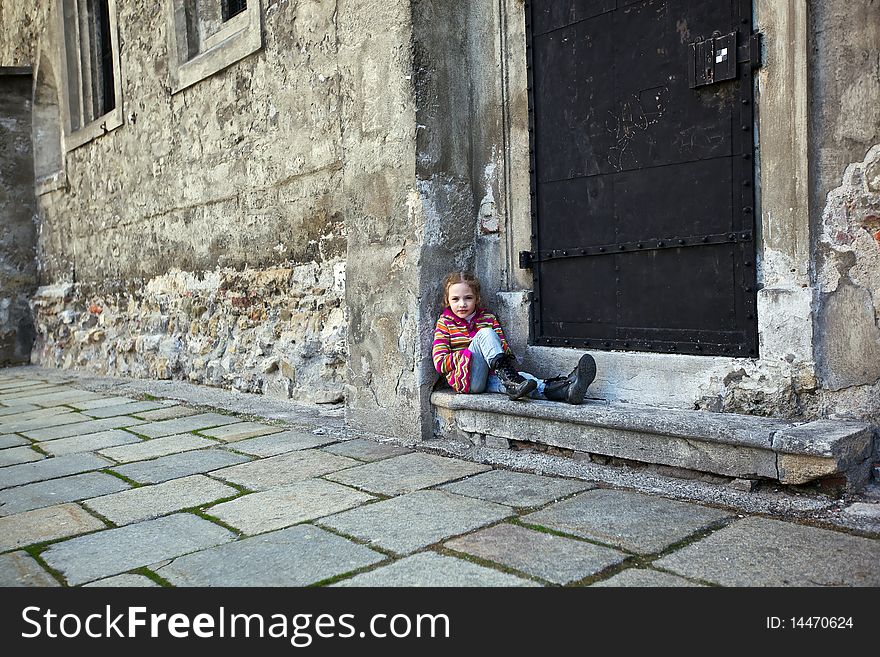 A girl sitting on steps on old wall background