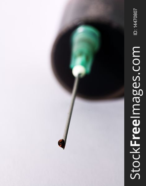 Drop of a red medicine on the end of a needle of a syringe. Drop of a red medicine on the end of a needle of a syringe