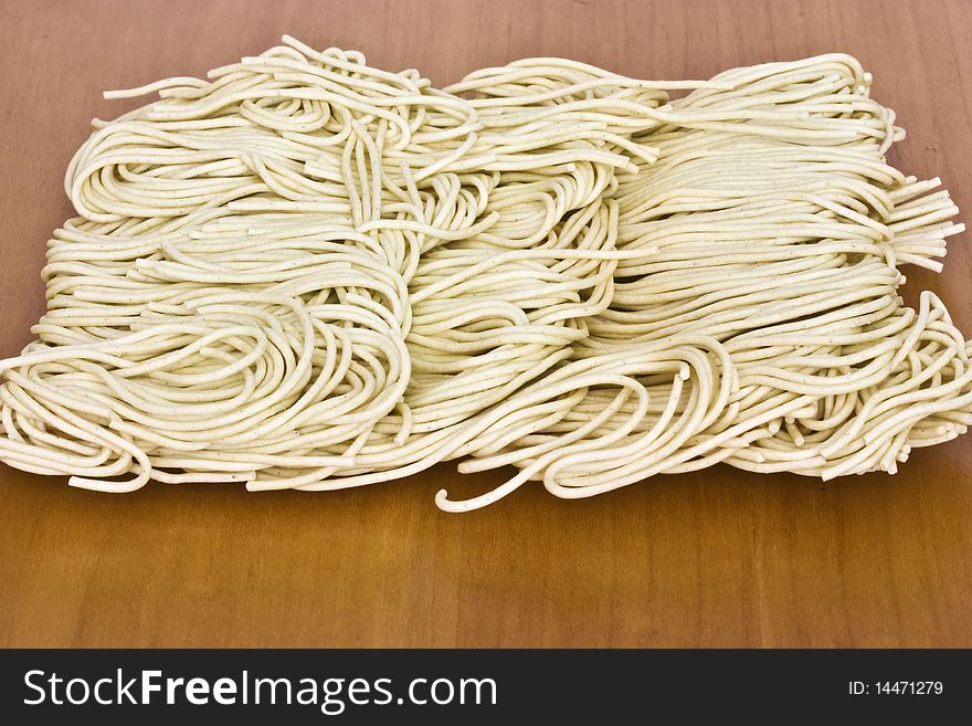 a macro picture of dried noodles on a wooden table. a macro picture of dried noodles on a wooden table
