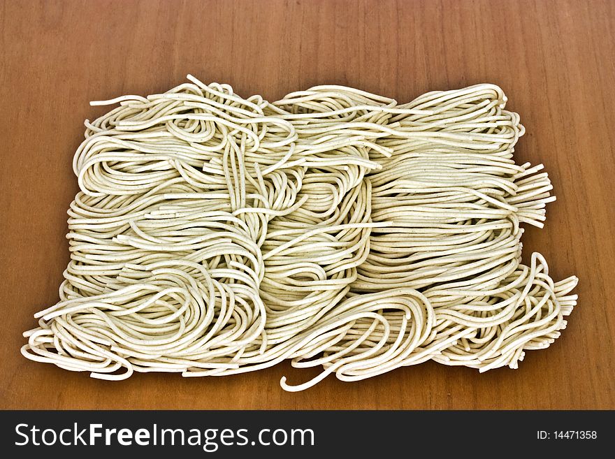 A macro picture of dried noodles on a wooden table. A macro picture of dried noodles on a wooden table