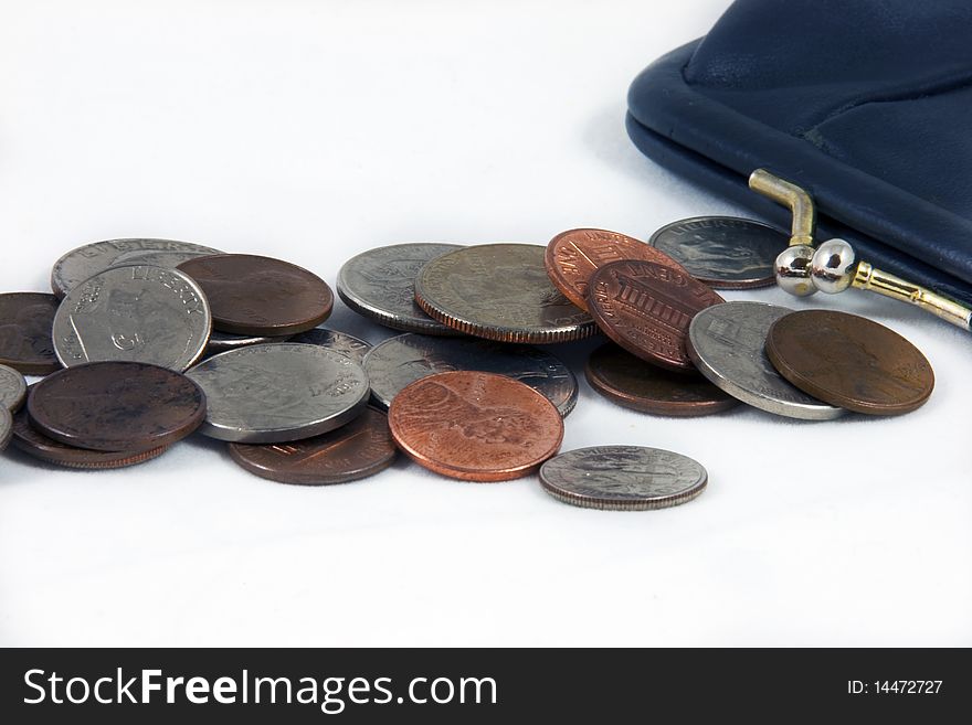 US coins and a navy blue closed money purse on an isolated white background. US coins and a navy blue closed money purse on an isolated white background