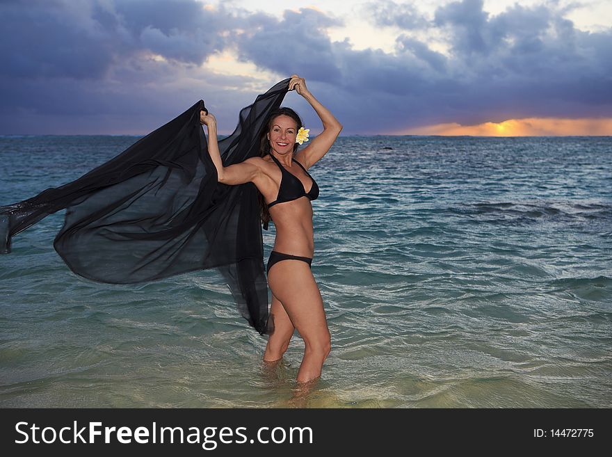 Beautiful forty year old woman in the ocean at sunrise in hawaii
